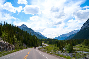 Beautiful view from a car on the Rocky Mountains in Banff National Park in Alberta. Panorama of a road in the mountains past a coniferous forest on a sunny day in summer.