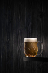 A frosty cold glass of light beer on a black wooden table