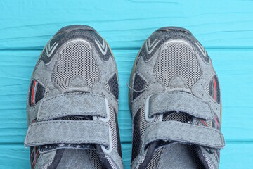 two small gray sneakers lie on a blue wooden table