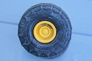 one old small black yellow wheel from a toy lies on a gray table