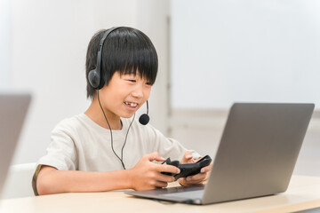 パソコンでゲームをするヘッドセットをした子供（男の子）
