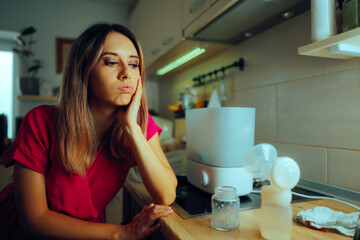 Tired Mother Next to Sterilizer, Baby Bottles and breast Pump. Complicated motherhood problems of a...