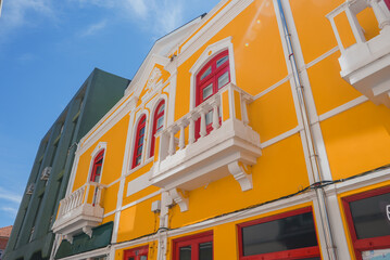 A stunning yellow building with white trim and red window frames in Aveiro, Portugal. Features...