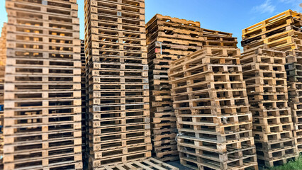 Wooden pallets. Factory and carefully arranged tall stacks of wooden pallets, ready for transportation and logistics