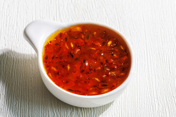 Delicious homemade sea buckthorn jam with whole berries in ceramic bowl on white table, closeup