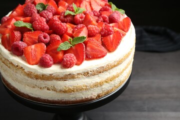 Tasty sponge cake with fresh berries and mint on dark gray table, closeup