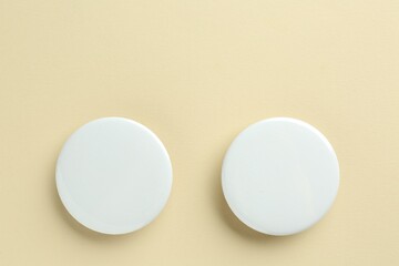 White button badges on beige background, flat lay. Mockup for design