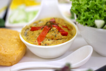 Steamed seafood curry in spoon on white plate Thai food background