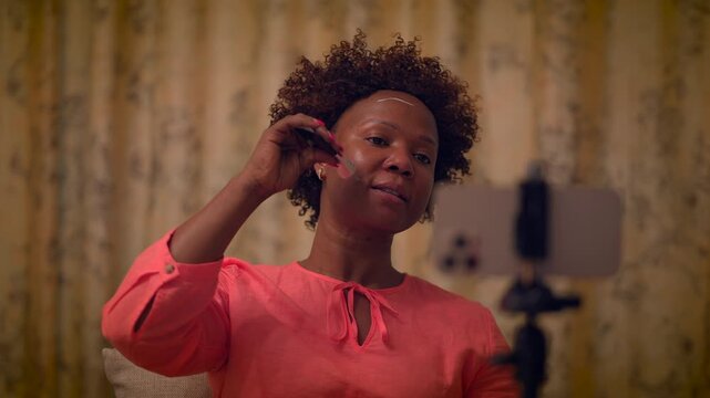 During the webinar, a woman demonstrates makeup techniques using a smartphone and makeup brush