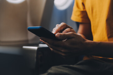 Attractive Asian businesswoman traveling on airplane playing with mobile phone while sitting in cabin.