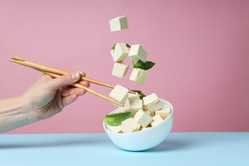 Cubes of tofu in a bowl on a pink background
