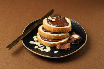 Bread with chocolate paste in a bowl on a brown background