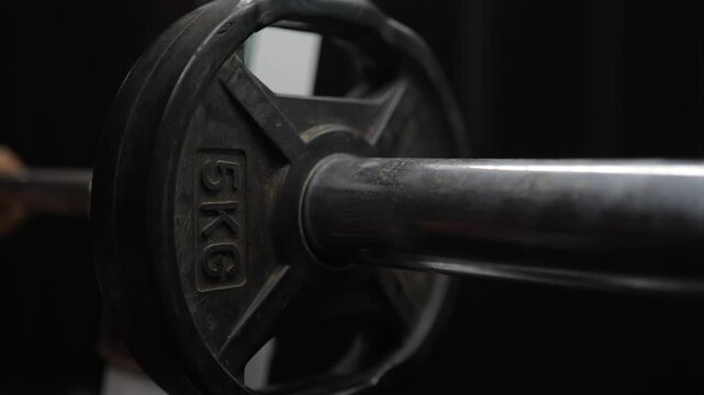 A strong and determined woman lifts 5-kilogram weights and lets them drop, showcasing her skill and strength in a workout setting