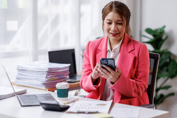 Business asian woman sitting in an office and using a phone, smartphone.