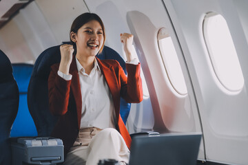 A young Asian woman, seated as an airplane passenger, contemplates dollar bills, reflecting on...