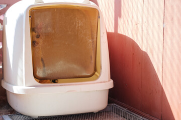 Enclosed cat litter box in sunlight, placed outdoors.