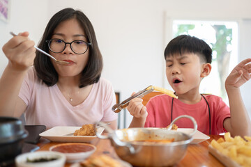 Mother and son eating Korean food together at a table, enjoying their meal.