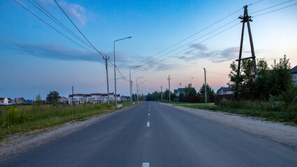 Empty curved wet asphalt road against the backdrop of a summer sunset