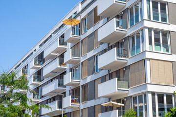 Modern multi-family apartment building with a yellow parasol seen in Berlin, Germany