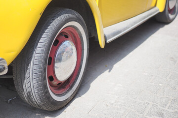 A classic vintage yellow car featuring a striking red accent on its wheel design