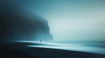 Solitary figure walking on a misty beach with a dramatic cliff in the background.