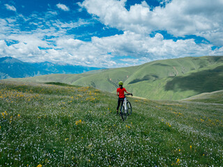 woman riding mountain bike on beautiful flowering grassland mountain top