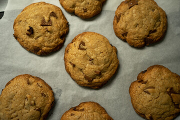 Freshly baked chip cookies on parchment paper.