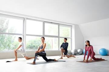 Obraz premium Group of sporty young people practicing yoga in gym