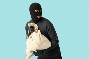 Male thief with bag on blue background