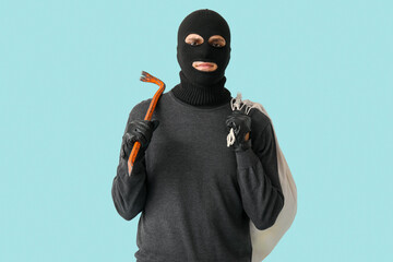 Male thief with bag and crowbar on blue background
