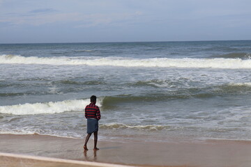 A man standing close to sea and enjoying waves in Varkala Kerala India