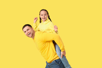 Obraz premium Father playing with his daughter on yellow background