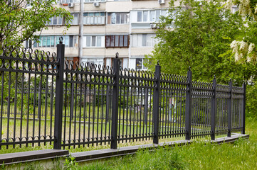 Metal fence in the city park. Decorative black iron guardrail for protection, close up