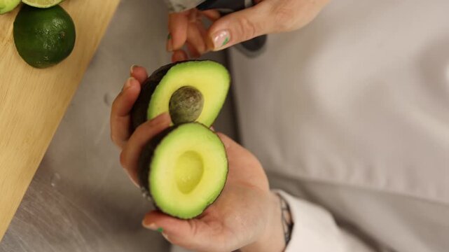 Chef Splitting A Ripe Avocado With A Sharp Knife In Hands. Closeup Shot.