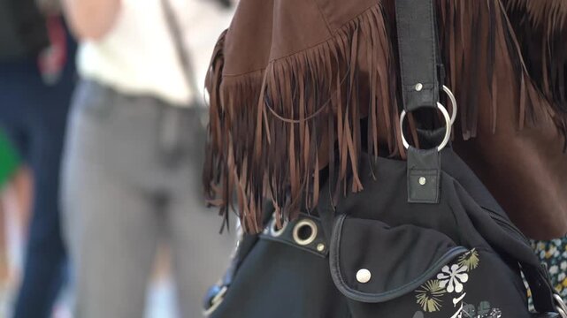 close up of a woman wearing leather brown jacket and black handbag