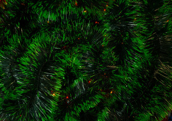 Green Christmas tinsel. The lights shine in the background.Christmas decor. Background. Close-up. Space for text.