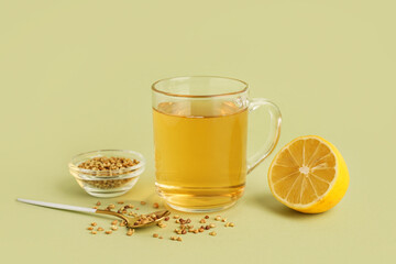 Glass cup of tasty buckwheat tea and lemon on green background