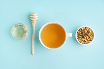 Cup of tasty buckwheat tea and honey on blue background