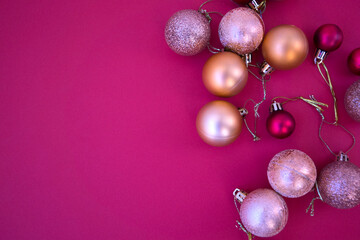 Gold and red Christmas baubles on a pink background. Close-up. Postcard. Copy Space