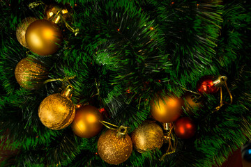 Multicolored Christmas tree toys on green tinsel. New Year's decor close-up. Copy space postcard