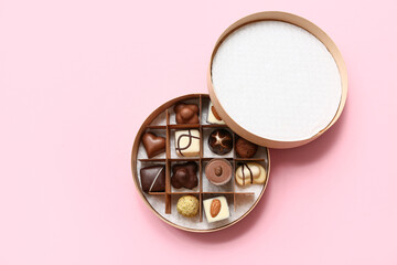 Box with delicious chocolate candies on pink background