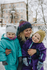 Happy family in warm clothes smiling at camera while playing on fresh air in winter snowy forest