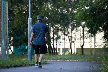 真夏の公園で散歩する一人のシニア男性の姿