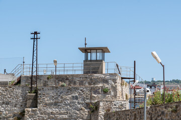 Historic watchtower on a stone fortification under a clear blue sky, with modern elements,...