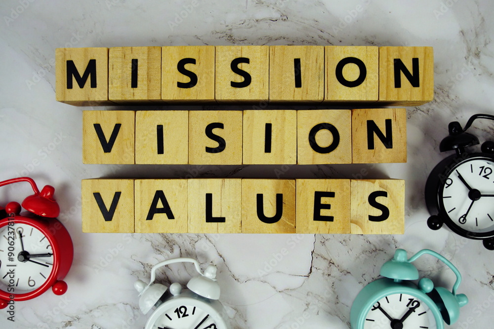 Poster mission vision values with wooden blocks alphabet letters and alarm clock on marble background