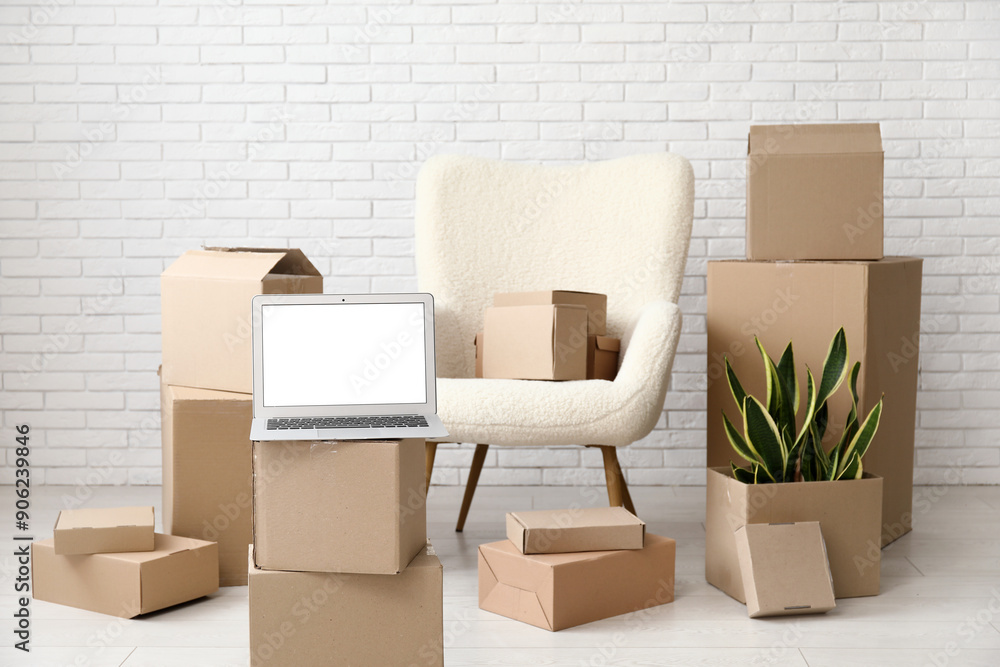 Canvas Prints Blank laptop with moving boxes and armchair near white brick wall