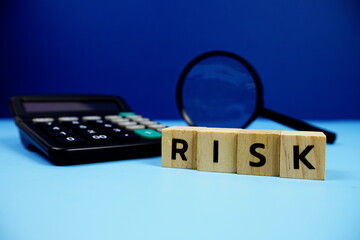 Risk with wooden blocks alphabet letters and Magnifying glass and calculator on blue background