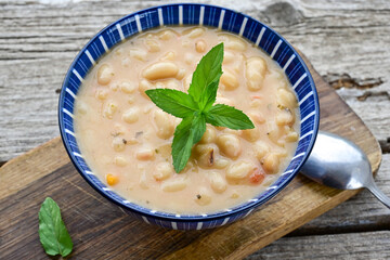   Homemade bean soup .Steamed white beans in tomato sauce  on a wooden background  