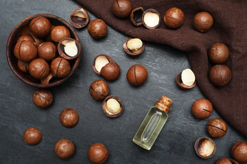 Bottle of oil with macadamia nuts on dark background