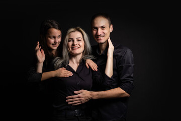 Happy young family with one child having fun together isolated on black.